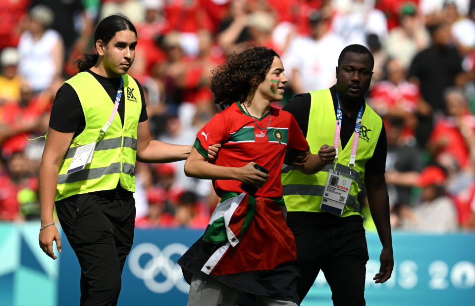 SAINT-ETIENNE, FRANCE - JULY 24: Stewards remove a pitch invader from the pitch during the Men's group B match between Argentina and Morocco during the Olympic Games Paris 2024 at Stade Geoffroy-Guichard on July 24, 2024 in Saint-Etienne, France. (Photo by Tullio M. Puglia/Getty Images)