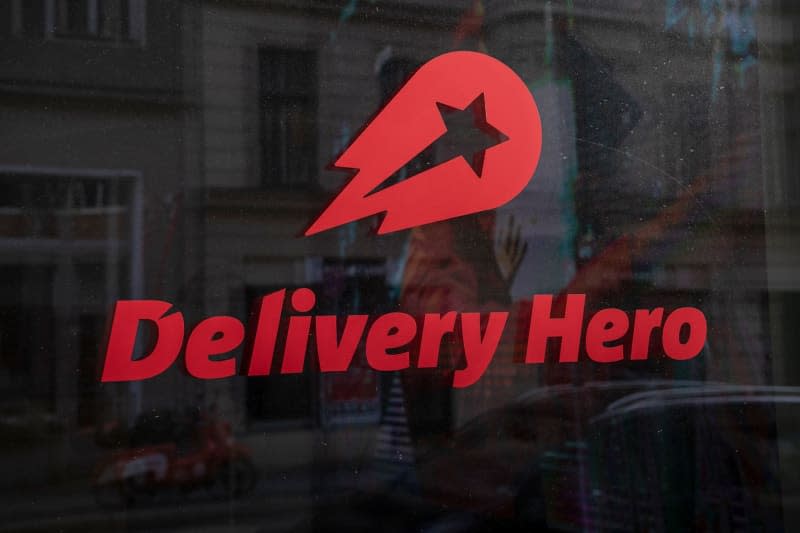 The logo and lettering of the food delivery service Delivery Hero can be seen in a window at the company's headquarters. Delivery Hero under EU investigation for alleged cartel activity. Paul Zinken/dpa-Zentralbild/dpa