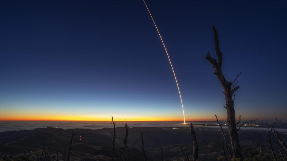  A rocket launches at night, leaving a streak of light through the sky. 