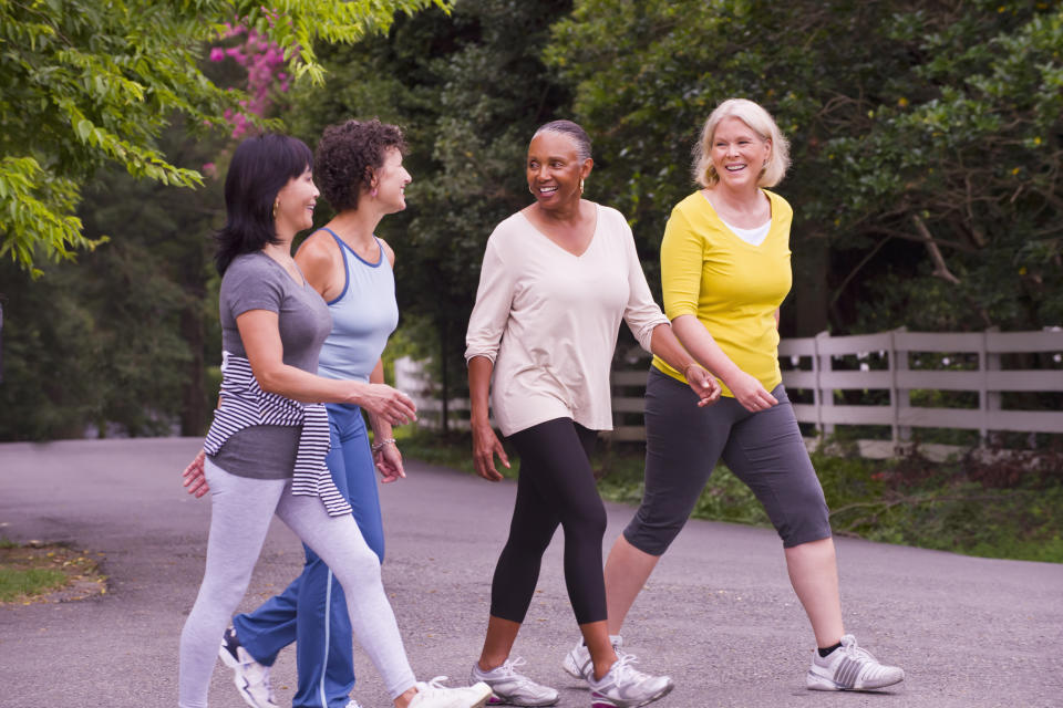 Four women in athleisure wear walking outdoors and chatting.