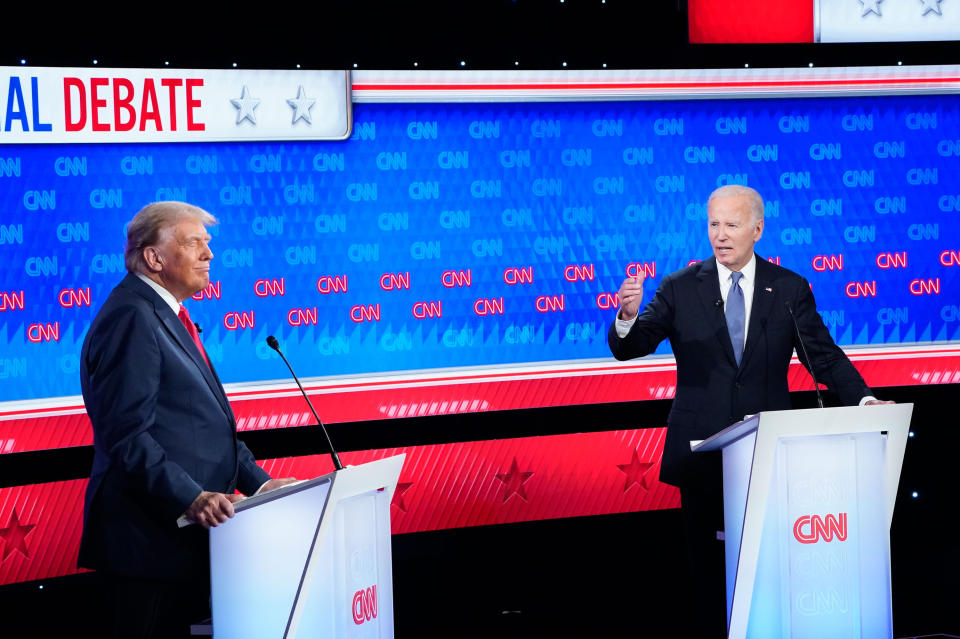 Biden looks at Former President Donald Trump as they both stand at podiums on the debate stage.