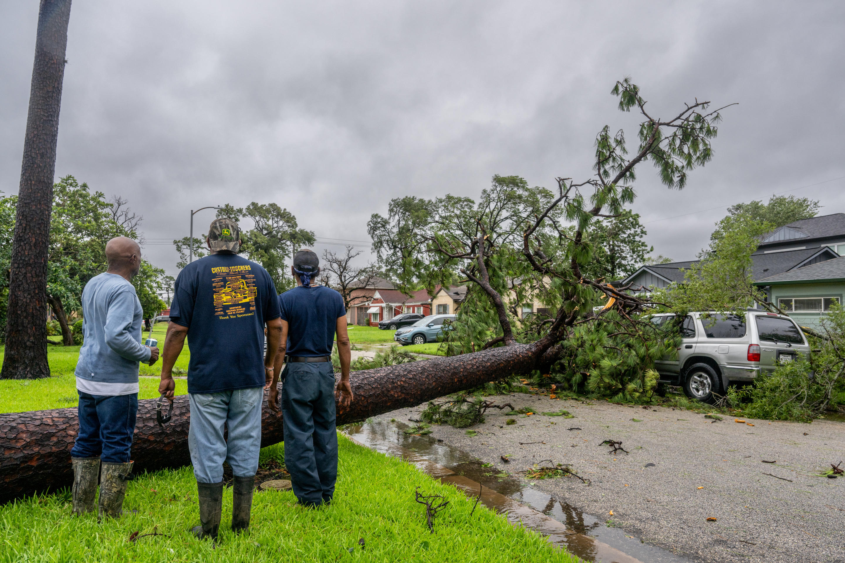 Residents assess a fallen tree in their neighborhood after Hurricane Beryl swept through an area in Houston on Monday.