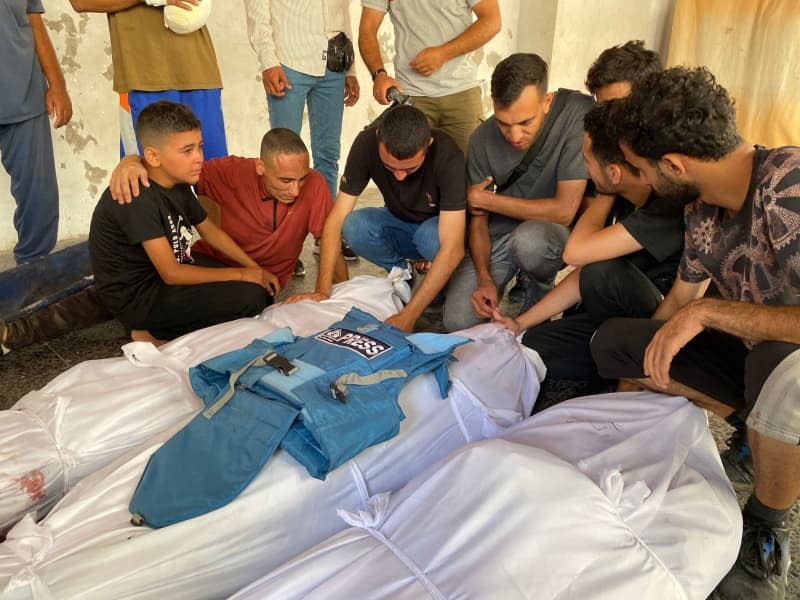 Mourners sit around the bodies of Palestinian journalists Saadi Modukh and Adeeb Sukkar who were killed during an Israeli attack. Hadi Daoud/APA Images via ZUMA Press Wire/dpa