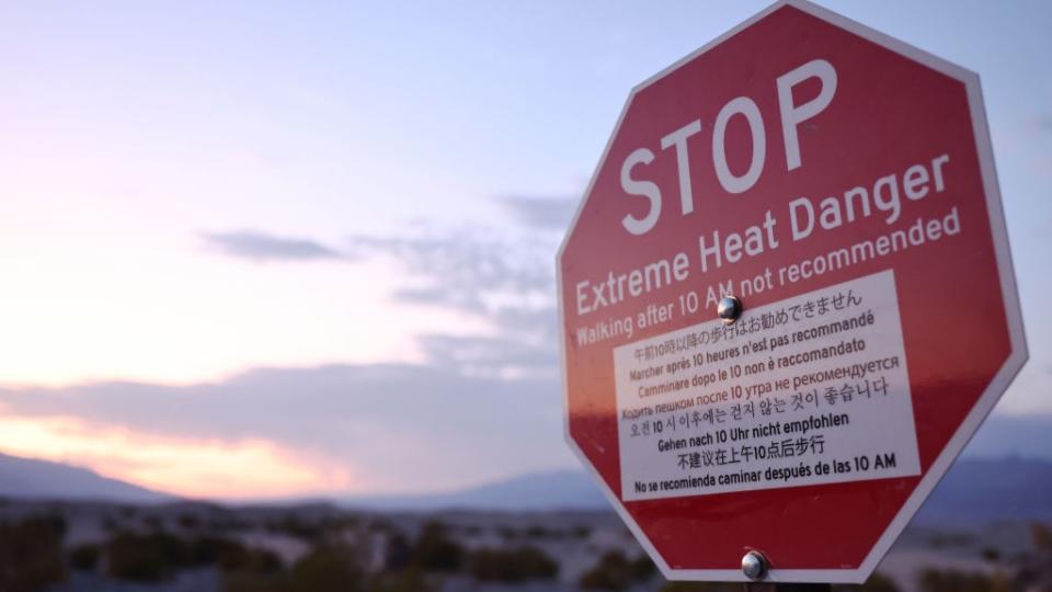 a red stop sign with the words stop extreme heat danger, walking after 10am not recommended is written in large white letters. The sentiment is repeated below in several different languages.