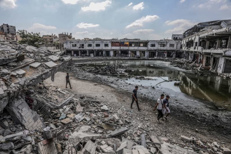 People walk between sewage and the rubble of destroyed buildings following the Israeli army's withdrawal from Khan Yunis. Abed Rahim Khatib/dpa