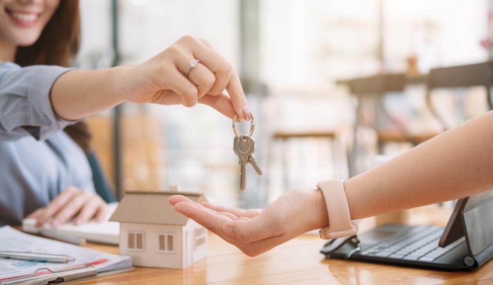 real estate agent handing new house keys to homeowner after signing documents