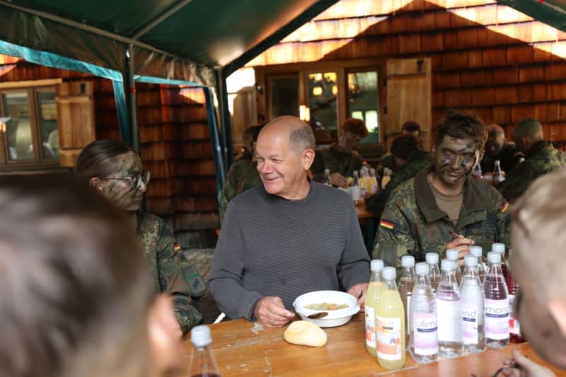 German Chancellor Olaf Scholz (C) eats lunch with mountain soldiers during a visit to the Bundeswehr's mountain infantry brigade. Alexandra Beier/AFP POOL/dpa