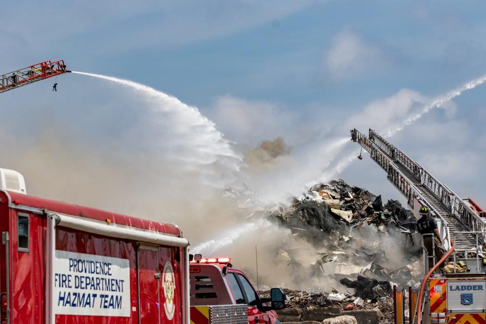 Ladder trucks spray hundreds of gallons of water a minute to douse a blaze that ignited from within a scrap metal heap at Rhode Island Recycled Metals on Wednesday.