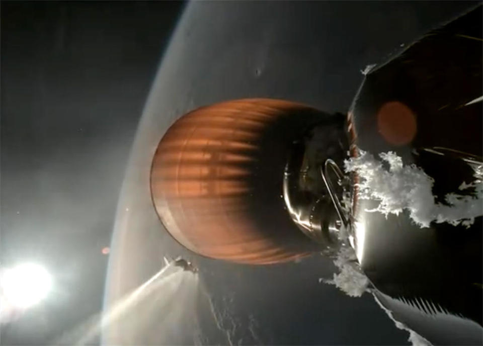 An unusual buildup of ice can be seen near the base of a Falcon 9 rocket's second stage during the first of two planned firings late Thursday, presumably caused by a liquid oxygen leak cited by SpaceX as the cause of an engine failure late in the climb to orbit. A large chunk of ice can be seen just to the left of the engine nozzle, vaporizing in the heat of its exhaust. / Credit: SpaceX