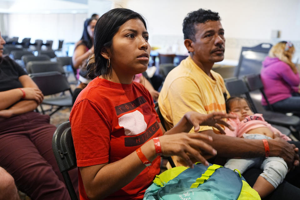 Brittany Gonzalez, front, speaks while her partner, Robinson San Juan, holds the couple's 1-year-old daughter, Triana Cataleya San Juan, during an orientation session for recent immigrants Monday, May 20, 2024, in Denver. (AP Photo/David Zalubowski)