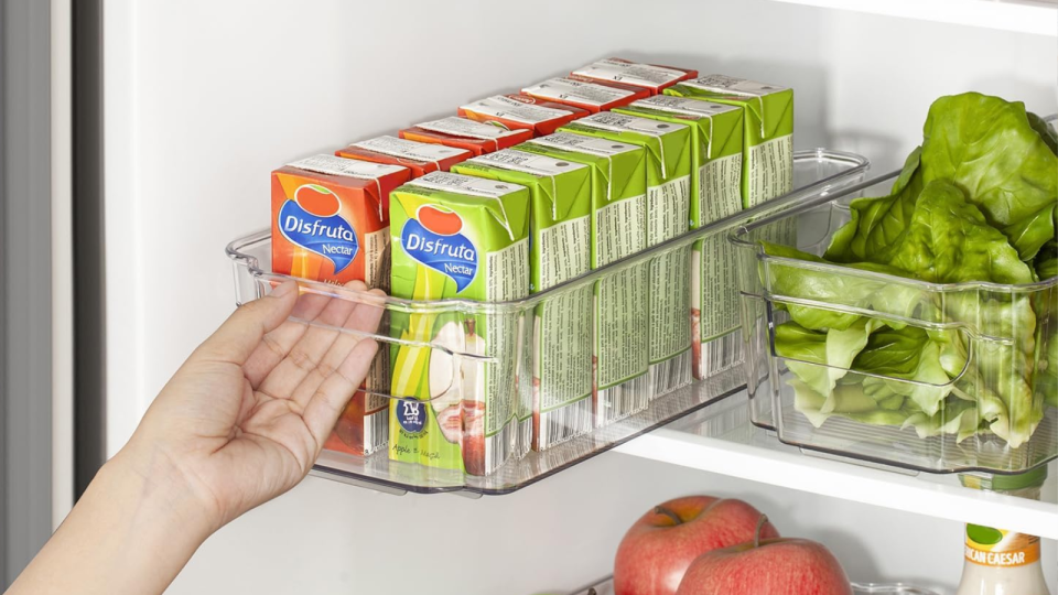 Someone pulling a fridge organizer filled with juice boxes by its handle