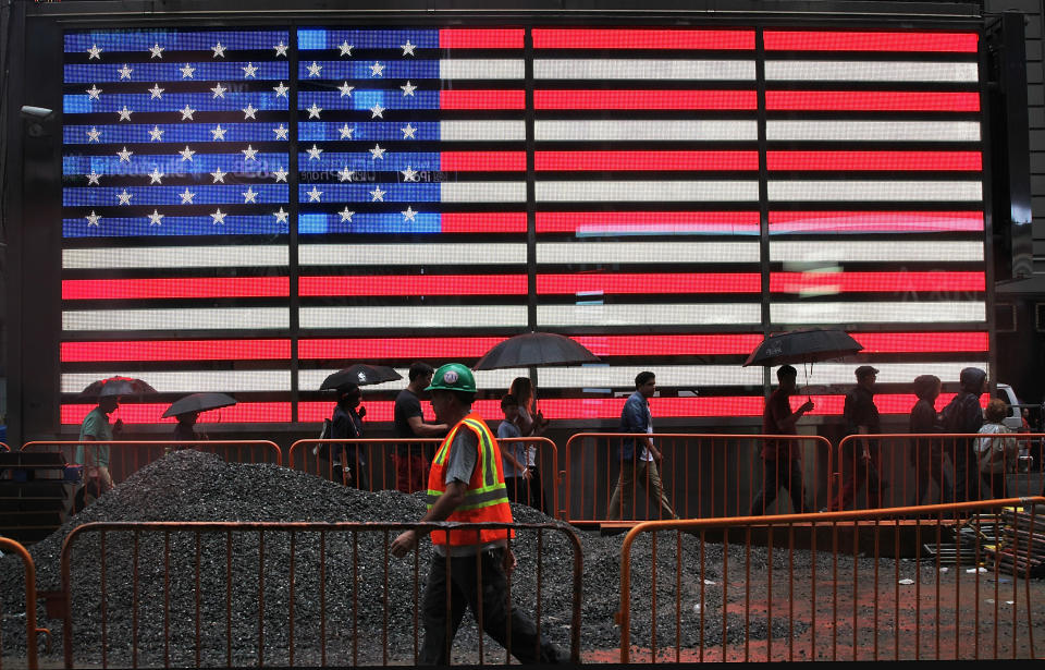 NEW YORK, NY - AUGUST 22:  Pedestrians and a construction worker walk past a lighted American flag in the rain in Times Square on August 22, 2013 in New York City. Afternoon rain which fell today in the city is expected to mostly clear by tomorrow.  (Photo by Mario Tama/Getty Images)