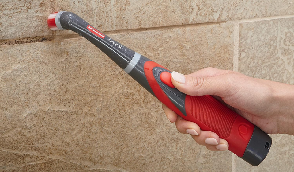 hand using the rubbermaid scrubber to clean bathroom grout