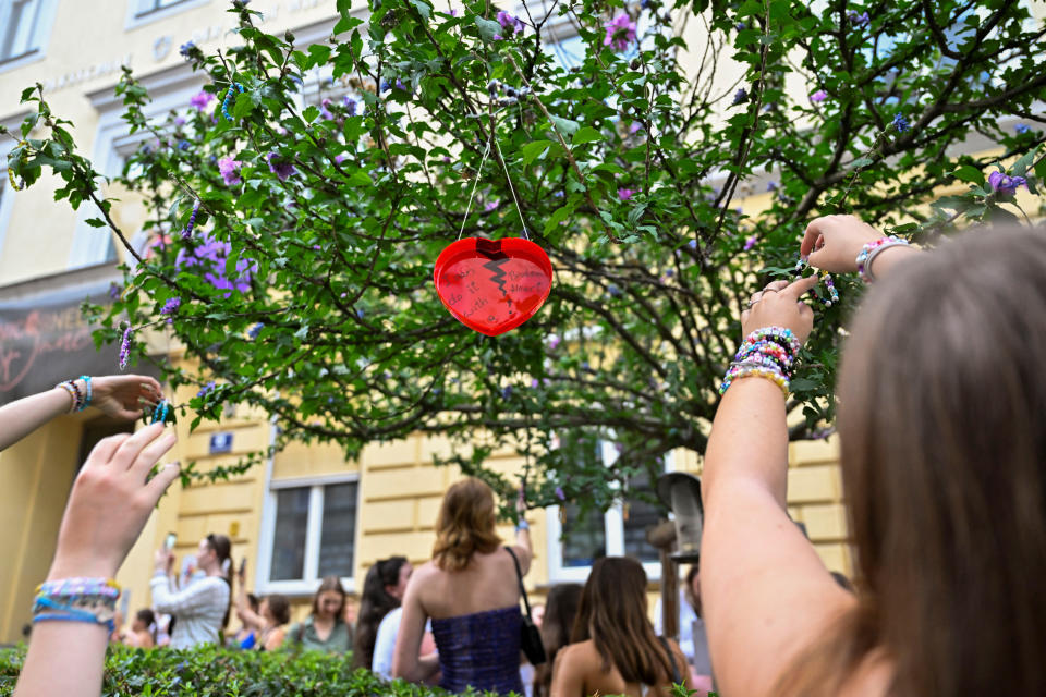 A few people putting bracelets on a tree.