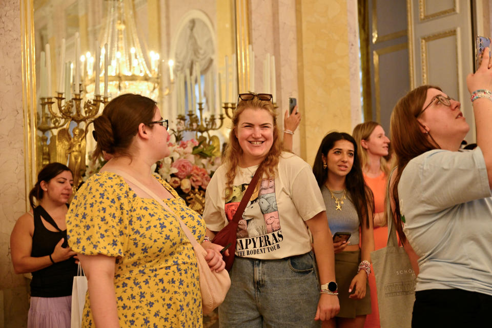 Half a dozen people stand in a room with a gaudy gilt interior.