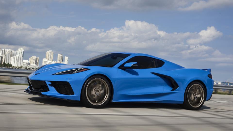 Side profile view of a 2024 Chevrolet Corvette Stingray in Rapid Blue driving over a bridge.