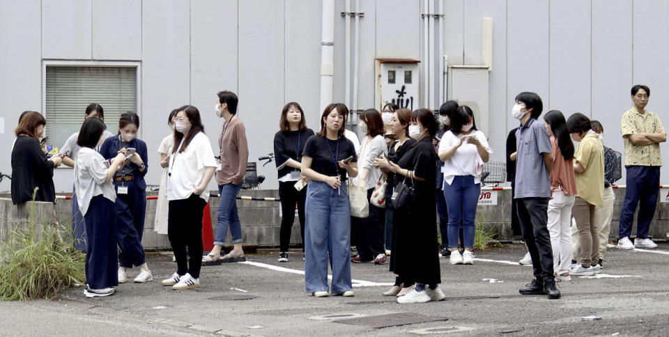 People stand outside after leaving a building following an earthquake (Kyodo News via AP)