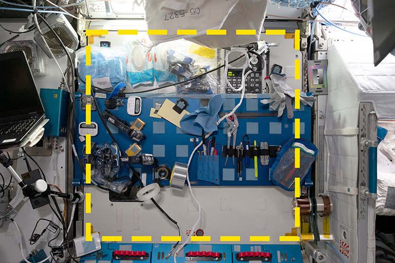 a wall in peg in the space station crowded with items. it is surrounded by an overlaid yellow square to illustrate the study area