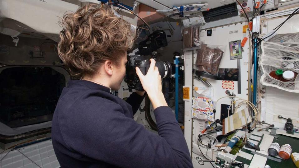 an astronaut with a camera aiming at a bunch of items mounted on a wall