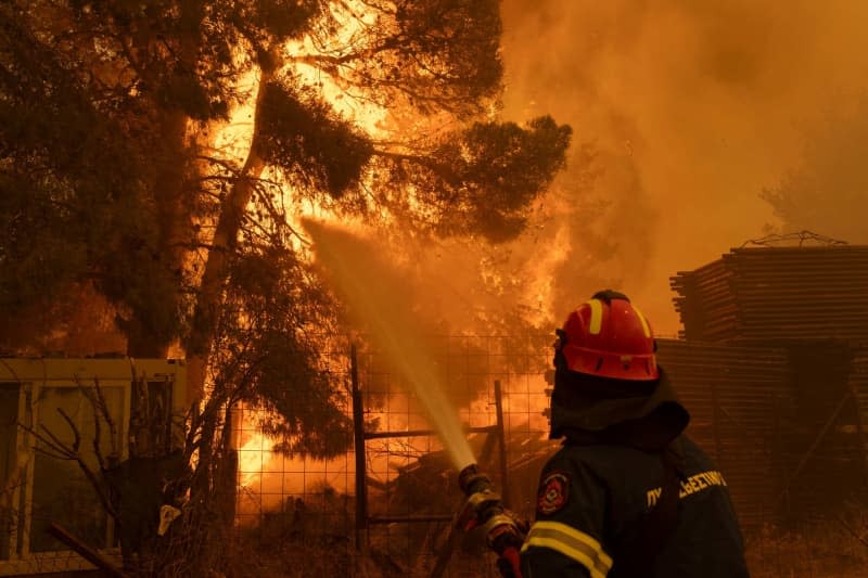 A firefighter extinguishes a large fire, just a few kilometers northeast of Athens. EU member states are sending aid to Greece to help emergency services in battling the country's biggest wildfire of the year on Monday, with multiple flash points burning across some 200 square kilometres of woodland north-east of the capital Athens. Socrates Baltagiannis/dpa