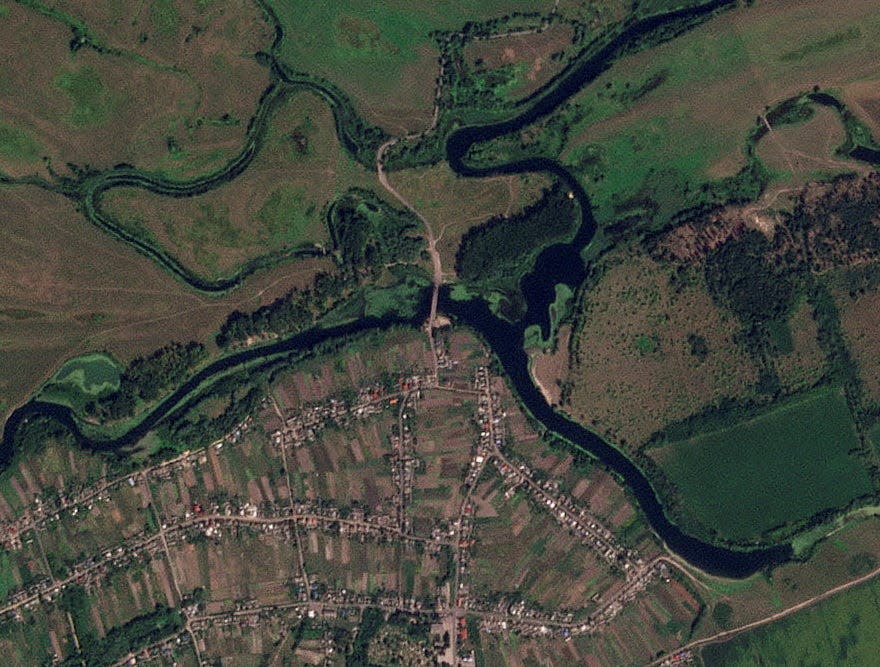 A satellite image of a strategic Russian bridge that was struck. There are black marks on the bridge.