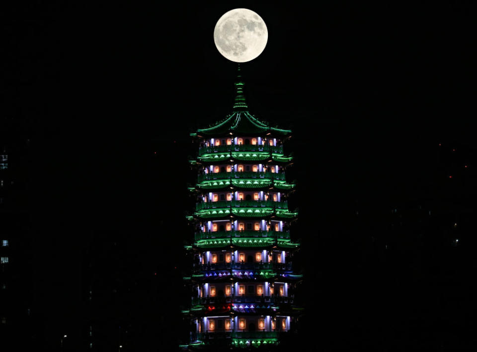 a tall temple structure with a large fully illuminated moon above.