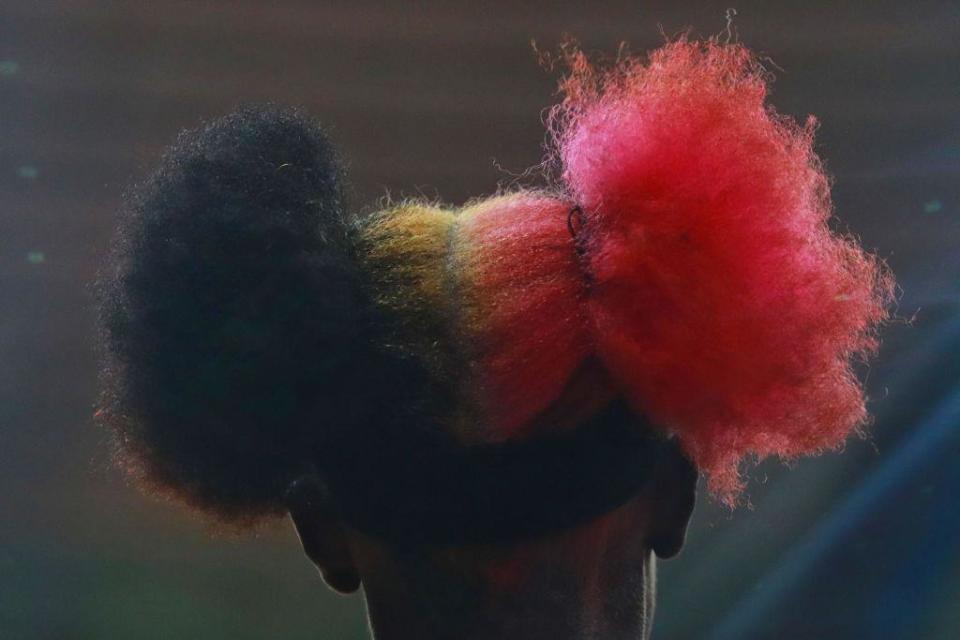 A woman wears her hair in two puffs - one is black, the other is pink.