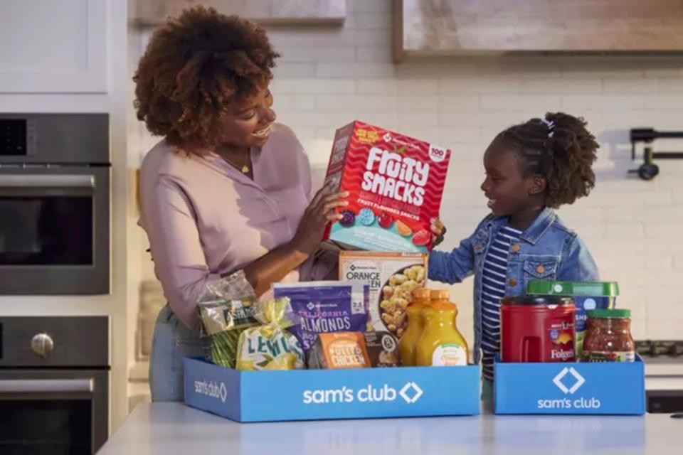 Mother and daughter in kitchen unpacking Sam's Club groceries.