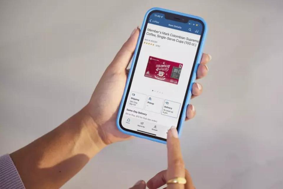 Hand holding a phone with the Sam's Club app.