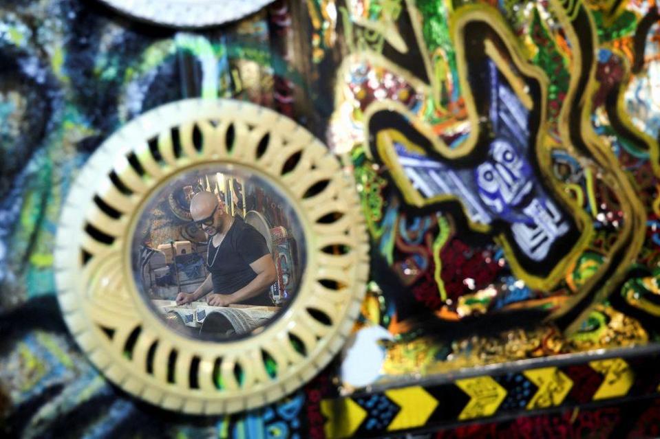 A man is reflected in a mirror made of recycled car tyres. 