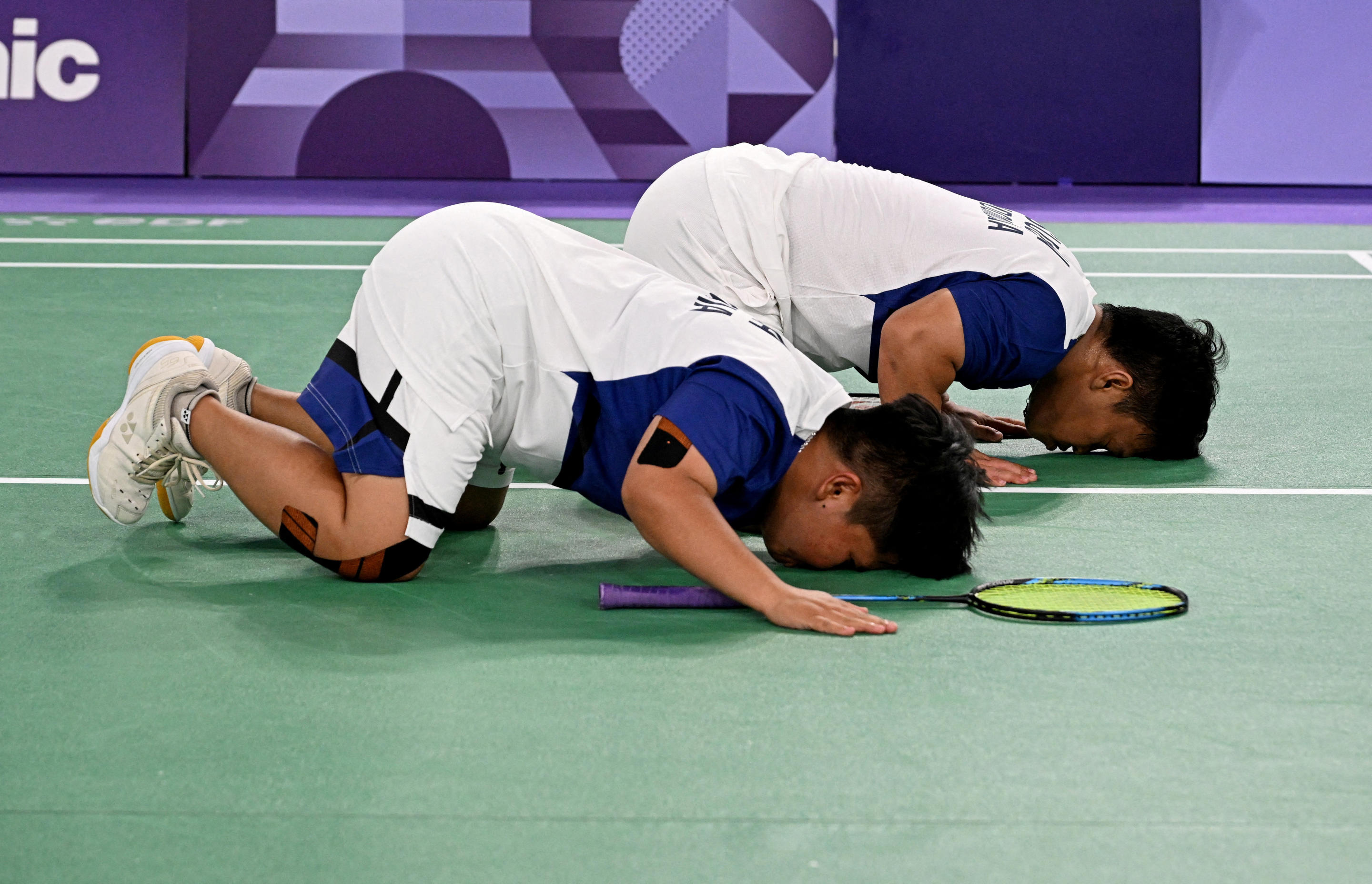 Two players bend down on the court.