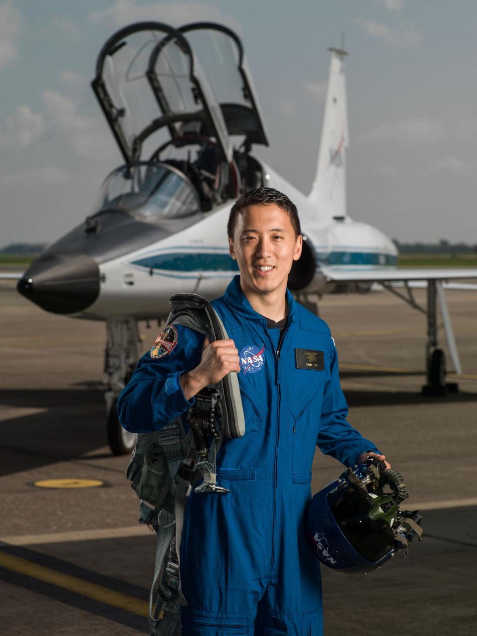 A person in a blue jumpsuit in front of a jet.