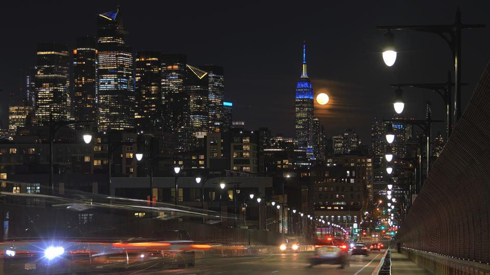  The full Worm Moon rises behind the skyline of midtown Manhattan and the Empire State Building in New York City as traffic drives down the 14th Street viaduct on March 25, 2024, in Hoboken, New Jersey. 