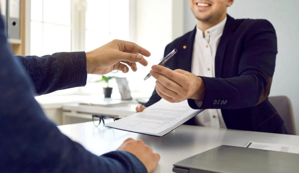 real estate agent handing homebuyer a pen to sign title insurance document