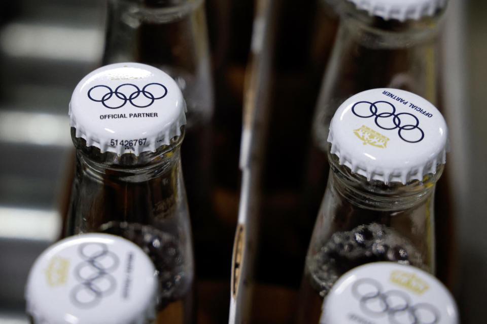 TOPSHOT - This photograph taken on April 23, 2024 shows crown caps covering beer bottles filled with Olympics logo on bottles of Corona Cero alcohol-free beer on a production line during a press visit at the Anheuser-Busch InBev (AB InBEV) brewery in Leuven. AB InBev, will be a World Olympic Partner until 2028. Corona Cero alcohol-free beer thus becomes a global sponsor of Olympic Games. (Photo by Kenzo TRIBOUILLARD / AFP) (Photo by KENZO TRIBOUILLARD/AFP via Getty Images)