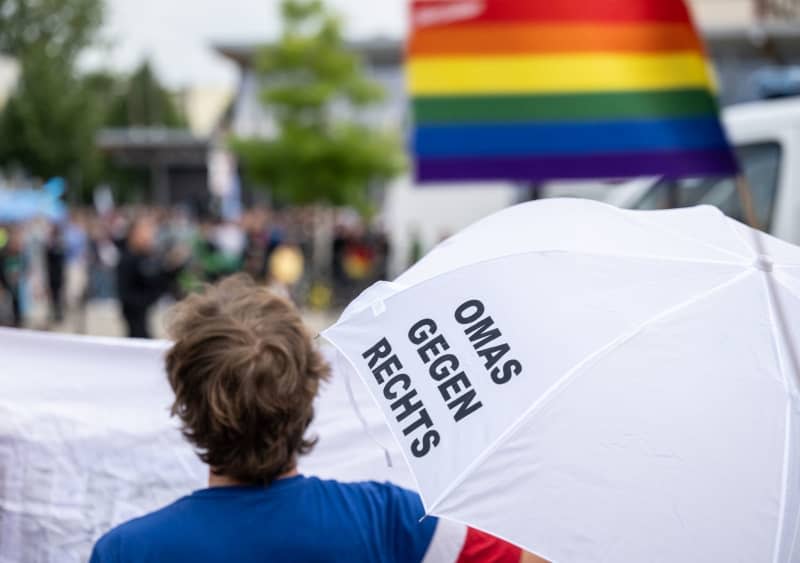 A participant in a counter-demonstration looks over a banner in the direction of the AfD election rally, ahead of the state parliament elections in Thuringia. Hannes P. Albert/dpa