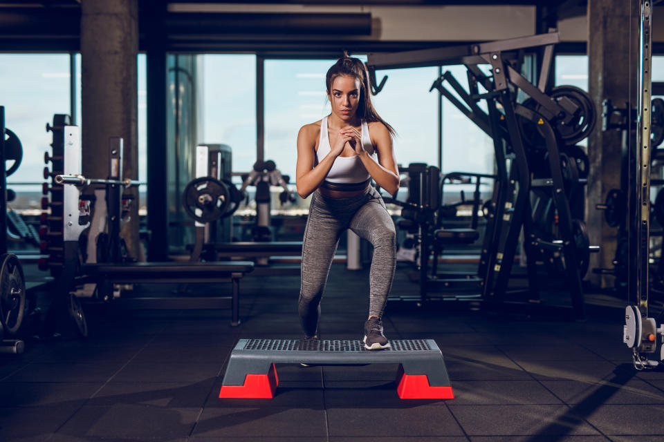 woman exercising on step aerobics equipment at gym