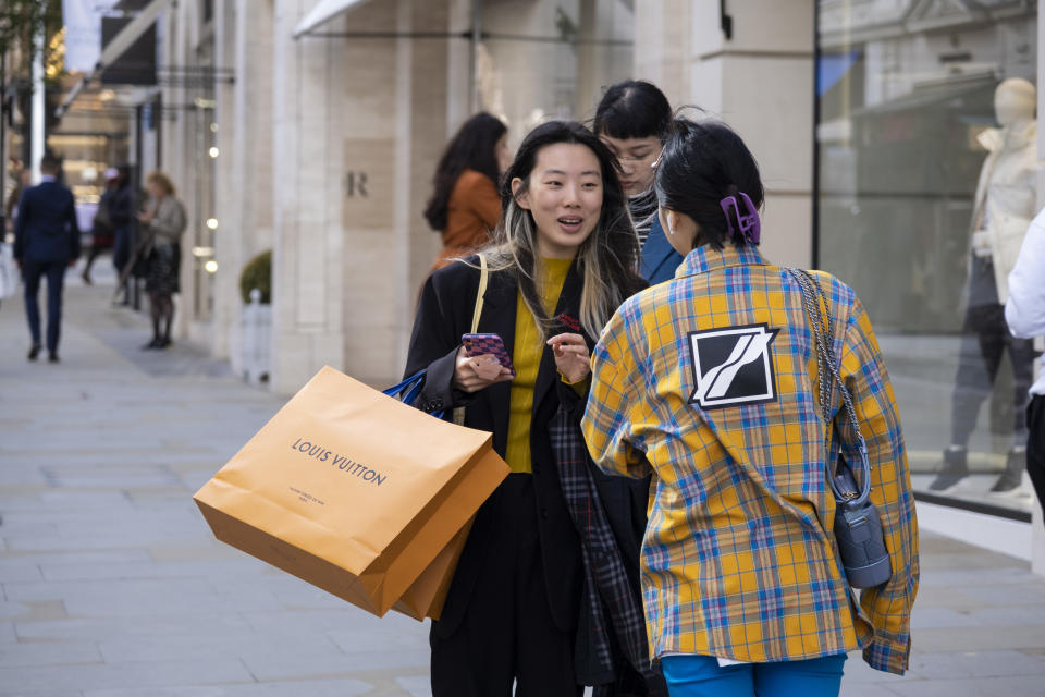 Fashion conscious young women, one with Louis Vuitton orange shopping bags, greet each other on Bond Street which is busier than any time over the last 18 months as shoppers come to the West End and retail business looks set to bounce back on 20th October 2021 in London, United Kingdom. Bond Street is one of the principal streets in the West End shopping district and is very upmarket. It has been a fashionable shopping street since the 18th century. The rich and wealthy shop here mostly for high end fashion and jewellery. (photo by Mike Kemp/In Pictures via Getty Images)