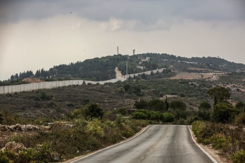 The Israeli erected border wall and an Israeli military post are seen from a deserted road of the Lebanese southern border village of al Bustan. p