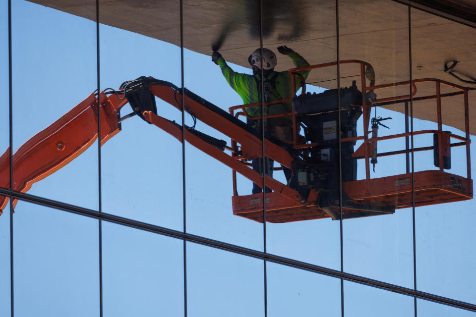 A construction worker works in the shade of a building as he keeps out of the sun and hot weather during the construction of a large office complex in the biotech sector of San Diego, California, U.S., July 2, 2024.  REUTERS/Mike Blake