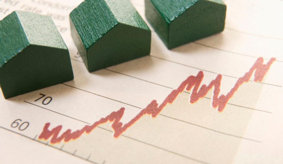 small wooden house models on paper showing line graph trending up