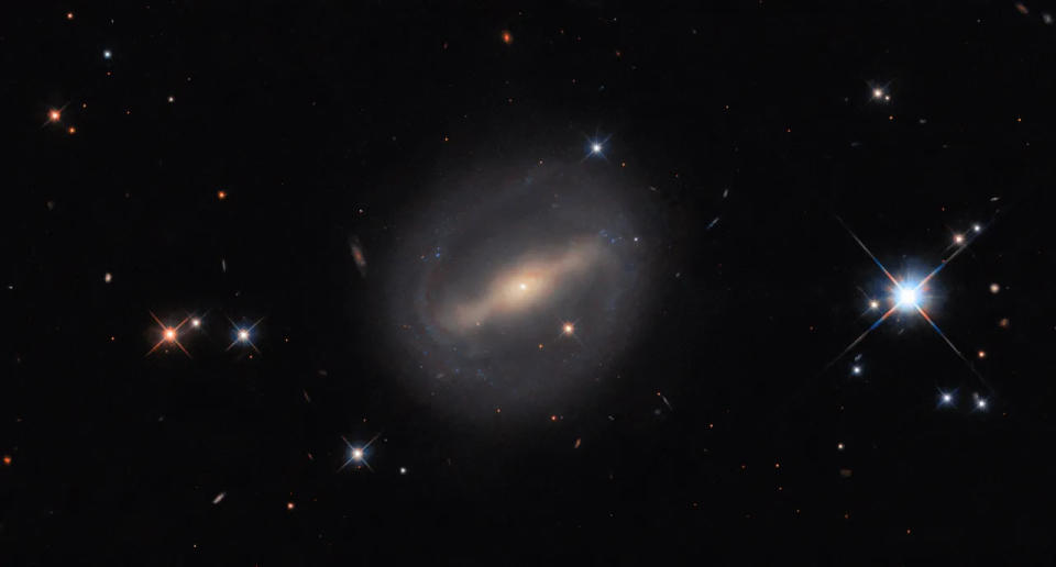  A hazy and glowing galaxy with a slight ring around it in space. 