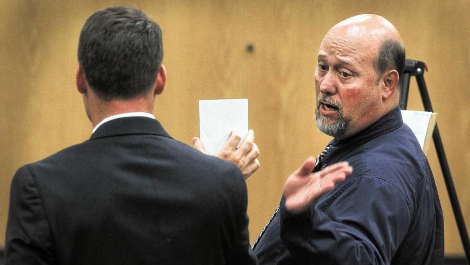 Gary “Scott” Goins’, right, talks about photographs shown to him by his attorney Brent Ratchford during his 2014 trial. Goins, 54, was found guilty and sentenced to a minimum of 34 years in prison for 17 child molestation charges.