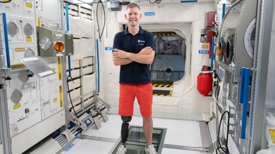 an astronaut standing in an iss module with a prosthesis on his right leg