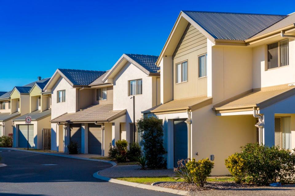 A view of a street showing a row of houses against a blue sky