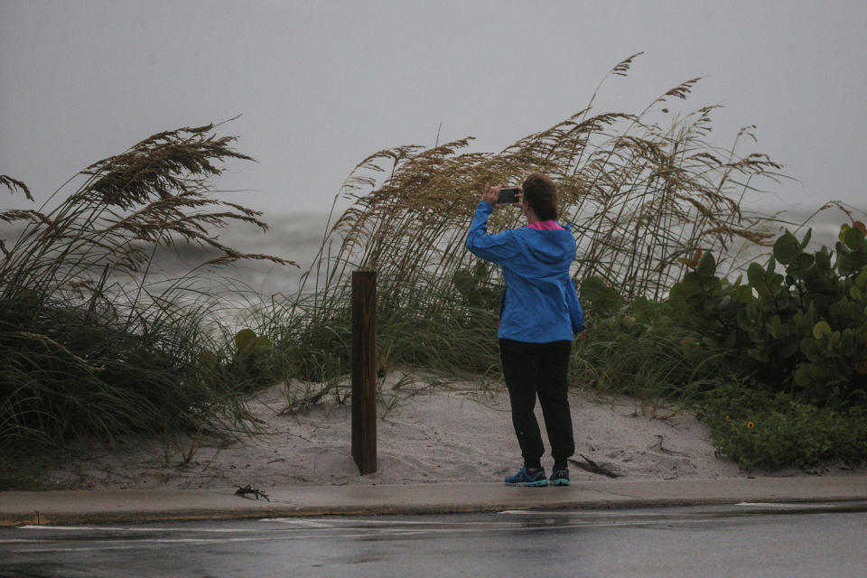 A person takes pictures of the stormy waters at the beach (Andrew West / The News-Press via USA Today Network)