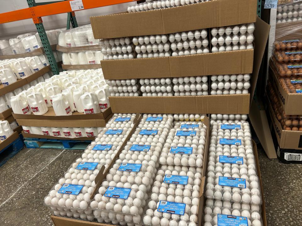 Cartons of Kirkland Signature cage-free eggs with jugs of milk in the background at Costco.