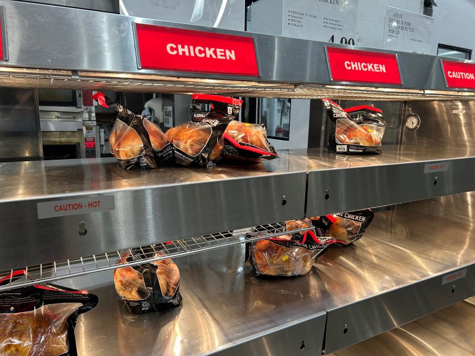 Kirkland Signature rotisserie chicken wrapped in bags on shelves at Costco.