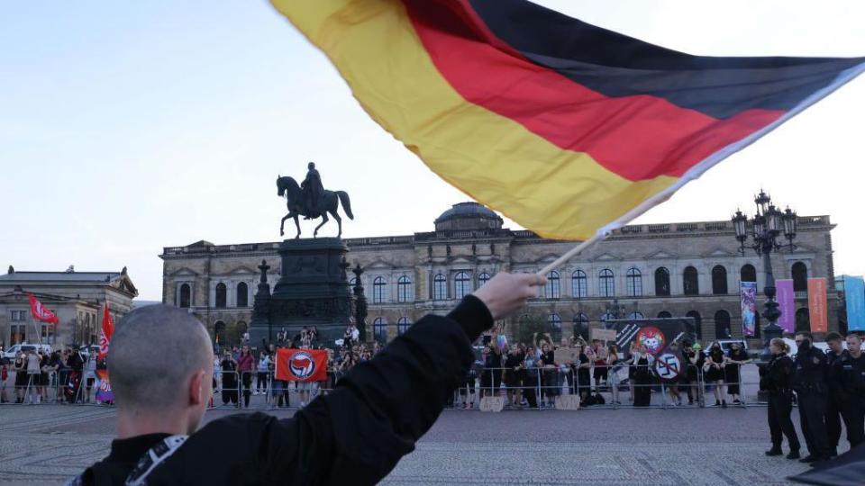 A man holds a German flag at a protest in Dresden