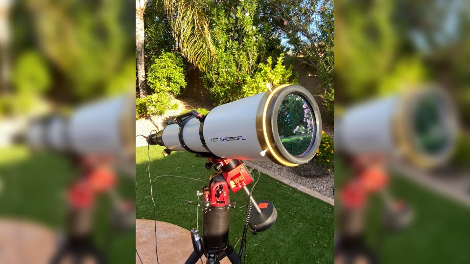 a white telescope in a grassy backyard